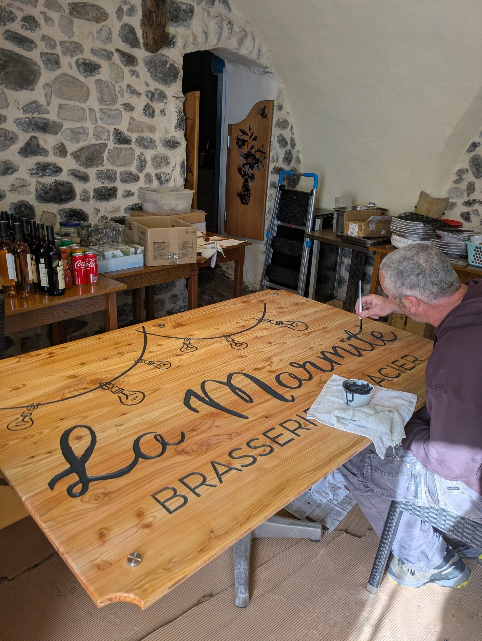 Client peignant une enseigne en bois gravée – Alba-la-Romaine
